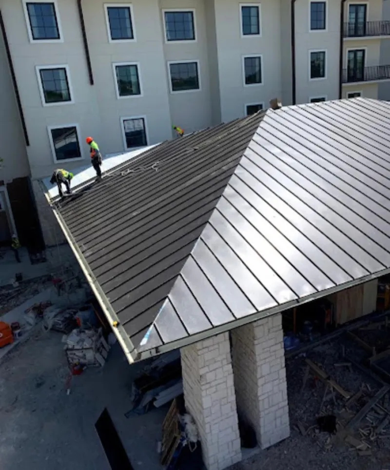 Crew installing standing seam metal roof panels on a commercial project in Oakland